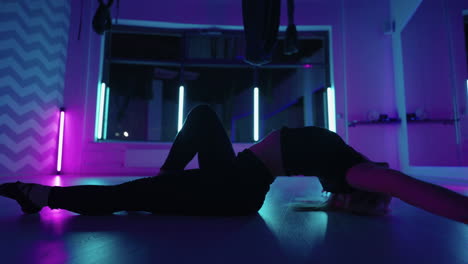 A-woman-dances-in-a-studio-with-a-neon-light-performing-graceful-exercises-and-movements-from-stretching-and-dancing-in-slow-motion